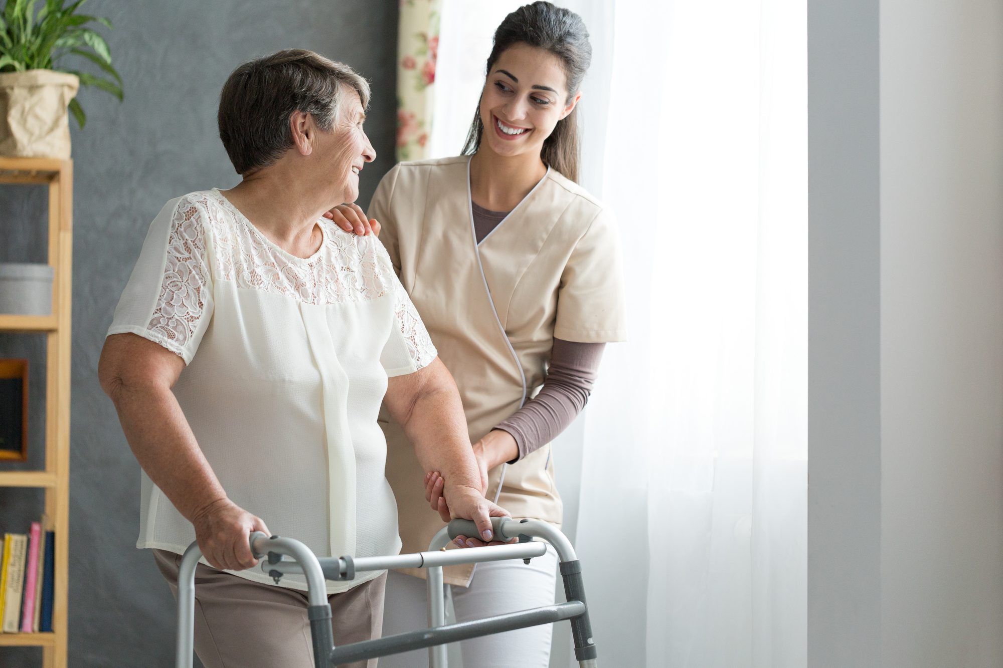 Smiling Nurse Helping Senior Lady to Walk Around the Nursing Home